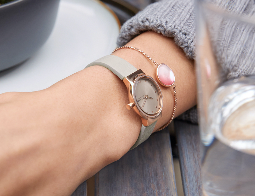 Minimalist-style man wearing Skagen watch featuring brown leather strap. Minimalist-style woman wearing Skagen watch featuring brown leather strap.