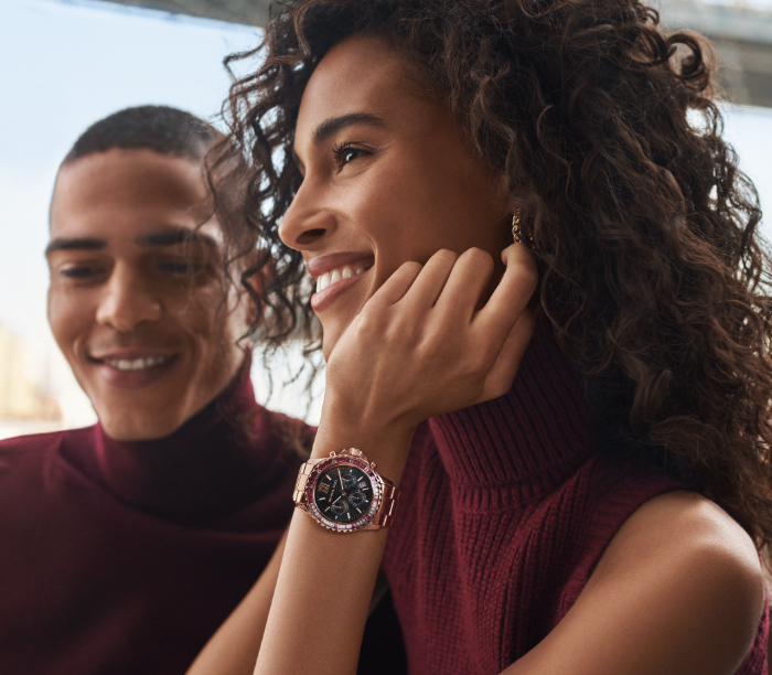 Woman wearing Michael Kors Bradshaw watch in rose gold-tone with a pink glitz topring.