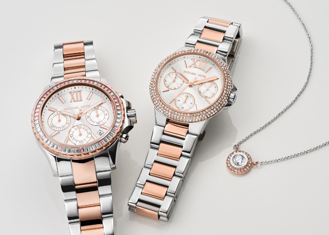 Two rose gold and silver tone Michael Kors watches on a white background.