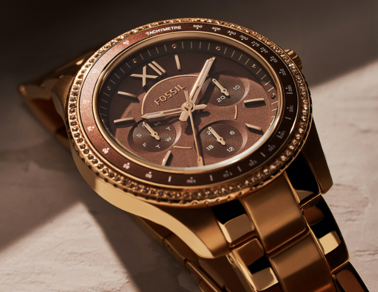 Femme élégante portant une montre Stella de Fossil doré rose.