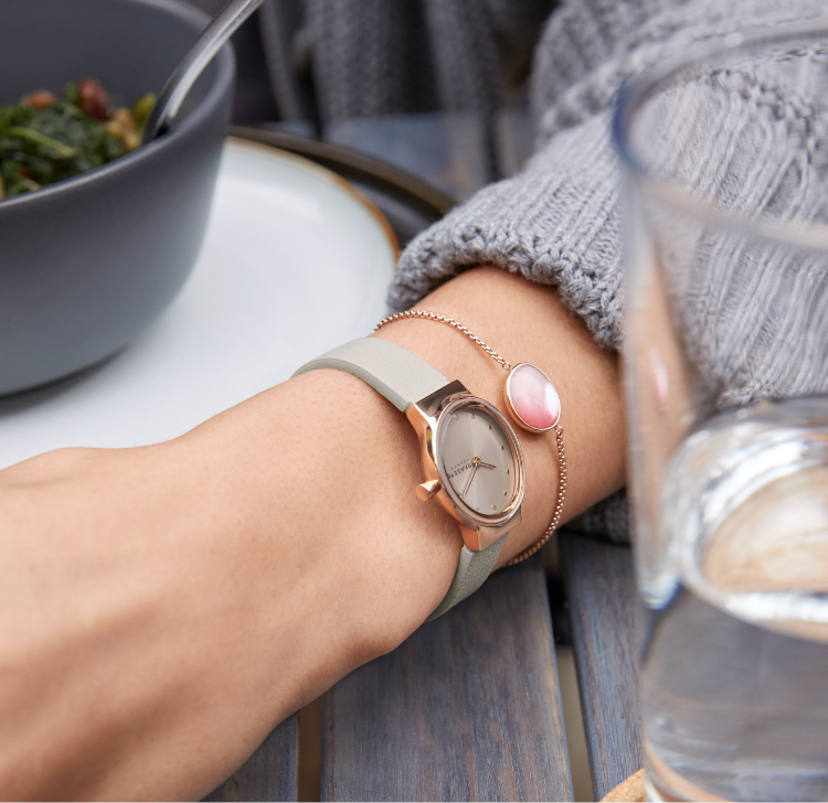 Woman wearing Skagen watch in smoke and rose gold-tone Skagen bracelet with soft pink mother-of-pearl detail.