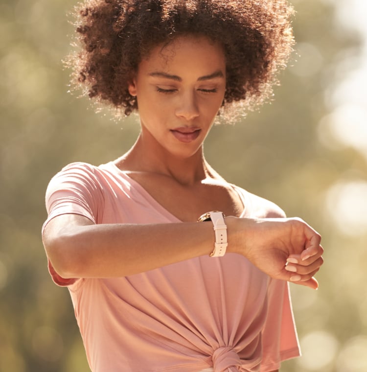 Fit woman wearing a Fossil smartwatch with a pink silicone strap.